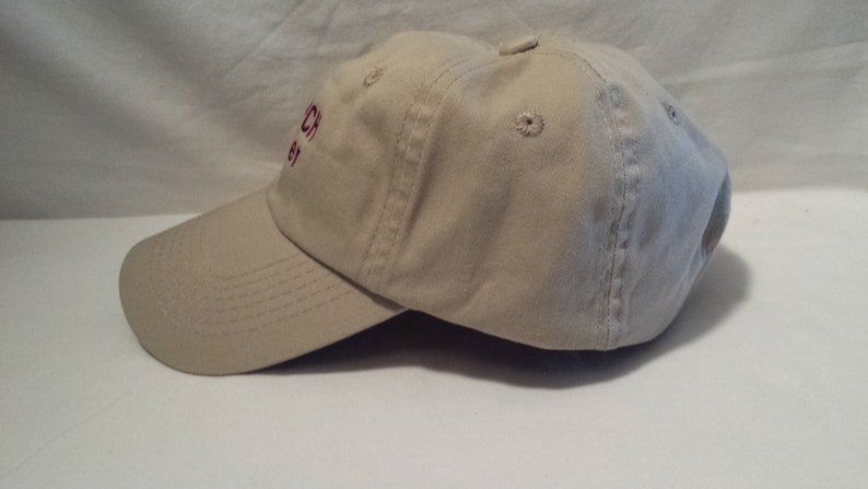 May include: A beige baseball cap with a red embroidered logo that says "Church 83".