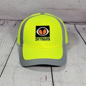 May include: A neon yellow baseball cap with a gray brim and accents. The cap features the word "SKYWARN" below a logo with an orange and white design.