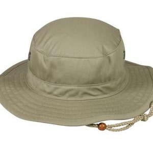 May include: A khaki-colored sun hat with a wide brim and a rounded crown. The hat features a chin strap with a wooden bead and is designed for outdoor activities. The hat's brim measures approximately 3 inches.