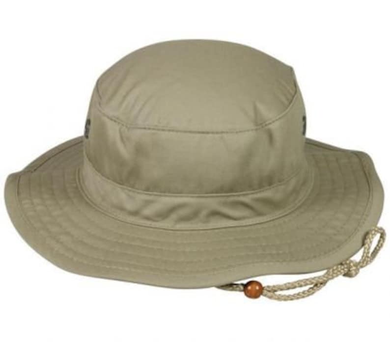 May include: A khaki-colored sun hat with a wide brim and a rounded crown. The hat features a chin strap with a wooden bead and is designed for outdoor activities. The hat's brim measures approximately 3 inches.