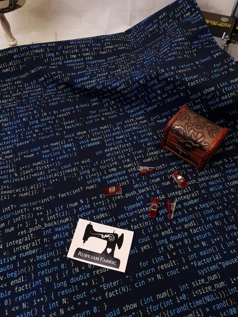 K&ouml;nnte beinhalten: Ein dunkelblauer Stoff mit wei&szlig;em Text darauf gedruckt. Der Text ist Code aus einem Computerprogramm. Der Stoff hat ein N&auml;hmaschinenlogo mit dem Text "Rubyjam Fabric" darauf gedruckt.