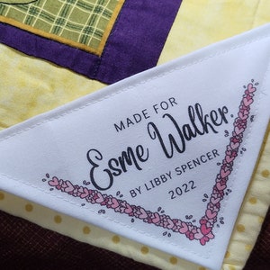 May include: White fabric label with black text that reads "Made for Esme Walker. By Libby Spencer 2022". The label is decorated with a border of pink hearts.