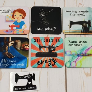 Puede incluir: Seis posavasos cuadrados de colores con diseños de costura. Los posavasos presentan imágenes de máquinas de coser, tijeras y texto como "¡Oh, puntada por favor!" y "¿Coser qué?"