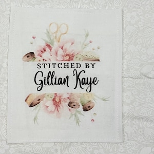 Pode incluir: Etiqueta de tecido branco com um design floral e o texto "STITCHED BY Gillian Kaye".