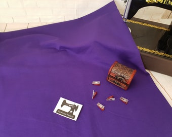 Könnte beinhalten: Ein violetter Stoffmuster mit einer kleinen Holzkiste und roten Nähklammern. Der Stoff ist glatt und hat einen leichten Glanz. Die Kiste ist mit einem Blumenmuster verziert. Der Text "Rubyjam Fabric" ist auf einem weißen Etikett gedruckt.