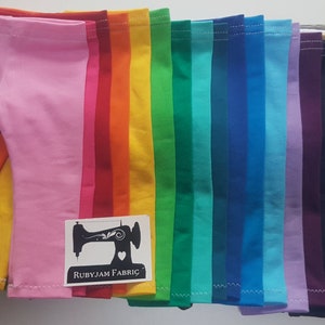 May include: A stack of 17 pairs of colorful leggings for dolls. The leggings are in a rainbow of colors, including pink, red, orange, yellow, green, blue, purple, brown, beige, and gray. The leggings are all folded in half and stacked on top of each other. The leggings are made of a soft, stretchy fabric. The leggings are perfect for adding a pop of color to any doll's outfit.  Rubyjam Fabric.