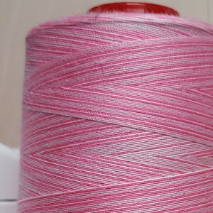 May include: A spool of pink and white striped thread.