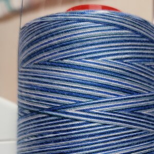 May include: A spool of blue, white and grey striped thread.
