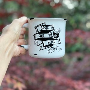 May include: White ceramic mug with black text and illustrations. The text reads "Basic Fall Bitch" with a pumpkin spice latte illustration.