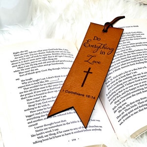 Könnte beinhalten: Ein braunes Leder Lesezeichen mit einem Kreuz und dem Text "Do Everything in Love" und "1 Corinthians 16:14".