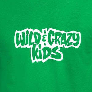May include: A bright green t-shirt with the text "WILD & CRAZY KIDS" in white, stylized lettering. The shirt is a solid color and has short sleeves and a crew neck.