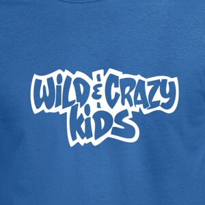 May include: Royal blue t-shirt with the text "WILD & CRAZY KIDS" in white, stylized lettering. The shirt is a solid color and has short sleeves. The text is in a playful, cartoonish font.