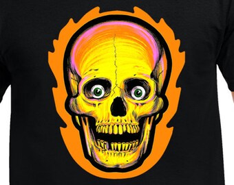 May include: Black t-shirt featuring a vibrant, stylized skull design. The skull is yellow and orange with green eyes, set against an orange flame-like outline. The design is centered on the front of the shirt.