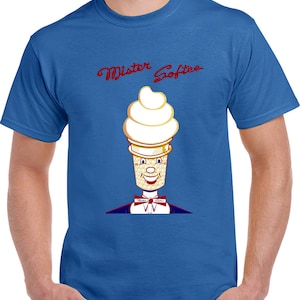 May include: Blue t-shirt featuring a cartoon ice cream cone character with a smiling face, bow tie, and the words "Mister Softee" in red script. The ice cream cone has a white swirl and a waffle cone base.