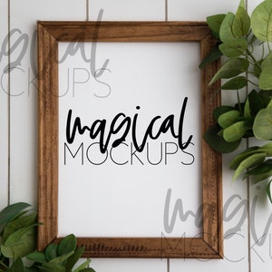 May include: A brown wooden frame with a white mat and a white background. The text "magical mockups" is written in black cursive font on the white background.
