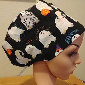 May include: Black scrub hat with a Halloween-themed print featuring white ghosts, bats, spiders, and the text "Boo-ooooop!"
