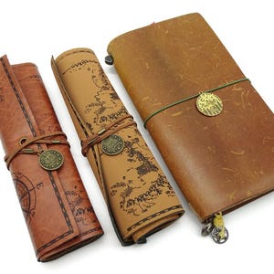 May include: Three brown leather journals with decorative metal charms. The journals are rolled up and have a map design printed on them.
