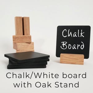 Puede incluir: Una pizarra negra con las palabras "Chalk Board" en escritura blanca, apoyada en un soporte de madera. También hay una pila de posavasos cuadrados negros y una estructura de bloques de madera. El texto "Chalk/White board with Oak Stand" está en la parte inferior.