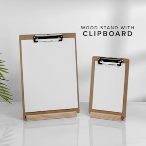 May include: Two wooden clipboards with white paper, displayed on a light-colored surface. The clipboards have a natural wood finish and metal clips. The text "WOOD STAND WITH CLIPBOARD" is displayed in black.