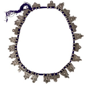 May include: A silver-toned necklace with a dark blue cord. The necklace features triangular and geometric shapes. The cord is a deep blue color, and the necklace is displayed against a white background. The necklace is a piece of jewelry.