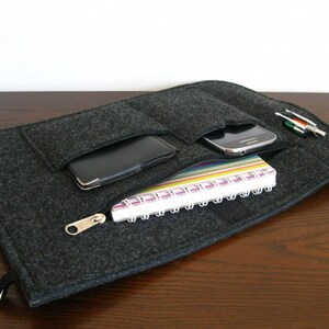 May include: A gray felt zippered pouch with multiple pockets for carrying a phone, notebook, and pens.