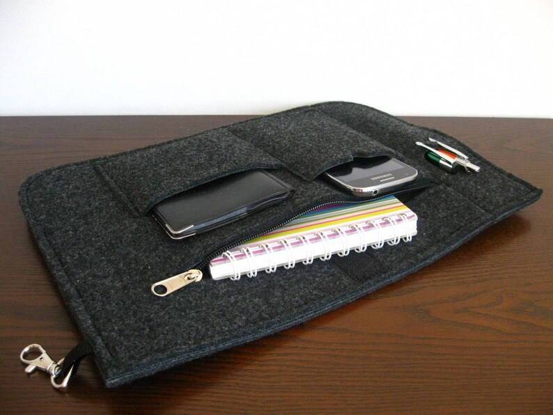 May include: A gray felt zippered pouch with multiple pockets for carrying a phone, notebook, and pens.