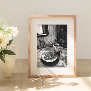 May include: A framed black and white sketch of a breakfast scene. A croissant and coffee cup sit on a table, next to a glass of water. A vase of white flowers and a pitcher are in the foreground.