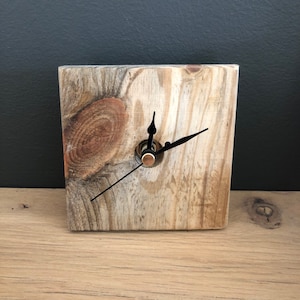 May include: A rustic wooden clock with black hands and a copper centre. The clock is made from reclaimed wood and has a natural, weathered finish.