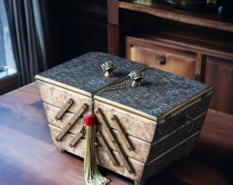 May include: A decorative wooden box with a hinged lid and intricate floral patterns. The box has a gold-colored trim and a red tassel hanging from the lid.