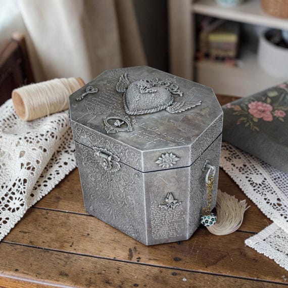 Intricately carved wooden sewing organizer with heart-and-wings motif that functions as both a keepsake box and a functional heirloom — the kind of piece that gets passed down.
