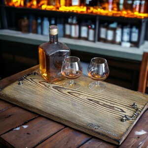 May include: A wooden serving tray with two clear glass glasses filled with amber liquid and a clear glass bottle filled with amber liquid. The tray has a dark wood finish and the text "Remarkable" is printed on the bottom right corner.