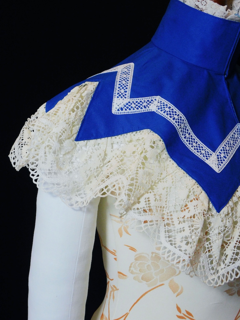May include: A white lace collar with a blue satin collar underneath. The blue collar has a white lace trim.