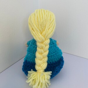 May include: A crocheted doll with a blue and teal dress and long yellow braided hair.