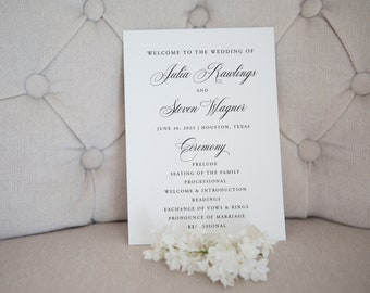 Peut inclure: Un programme de cérémonie de mariage avec les noms Julia Rawlings et Steven Wagner, la date du 30 juin 2022 et le lieu Houston, Texas. Le programme liste l'ordre des événements de la cérémonie, y compris le prélude, la mise en place des familles, le cortège d'entrée, l'accueil et l'introduction, les lectures, l'échange des vœux et des alliances, la proclamation du mariage et la sortie des mariés.