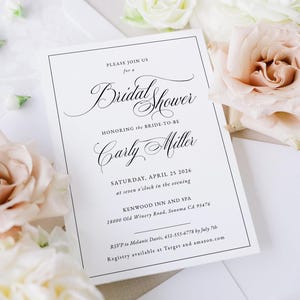 May include: A white bridal shower invitation with black text and a black border. The invitation includes the text "Bridal Shower" and the name "Carly Miller". The date and time are also included, along with the location and RSVP information.