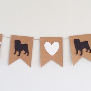 May include: A brown and white banner with alternating images of a pug, a bone, a heart, and a pug. The banner is strung together with white twine.