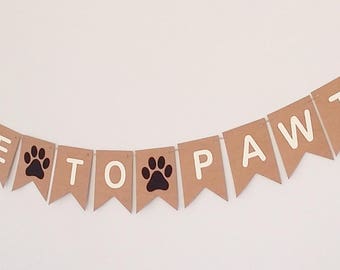 May include: A brown paper banner with the text "Time to Pawty" in white letters. The banner has black paw prints between the words.