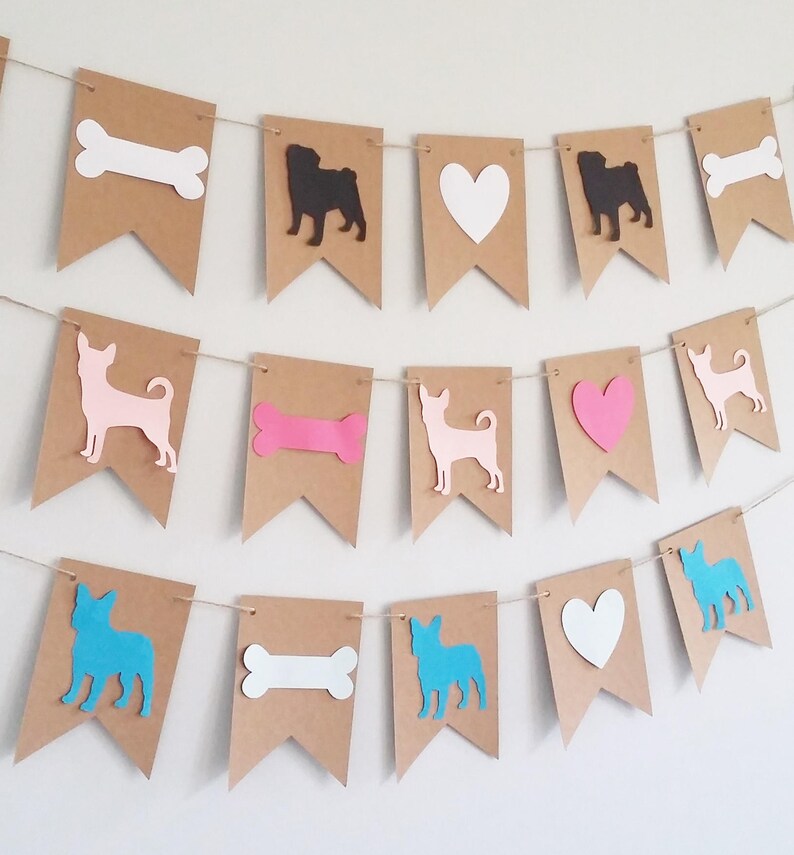 May include: A brown paper banner with cutouts of dogs, hearts, and bones. The dogs are a black pug, a pink chihuahua, and a blue french bulldog. The hearts are white and pink. The bones are white and pink.