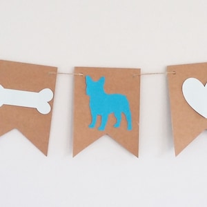 May include: A brown paper banner with blue and white cutouts. The banner features a dog, a bone, a heart, and a dog.