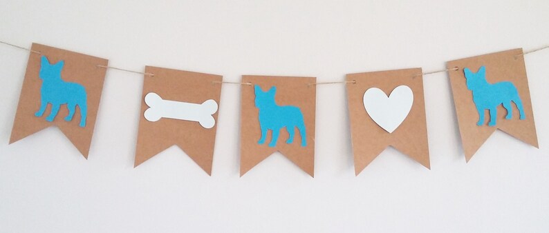 May include: A brown paper banner with blue and white cutouts. The banner features a dog, a bone, a heart, and a dog.