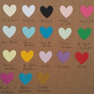 May include: A chart of 15 different colored heart shapes with the color name written below each heart. The colors include cream, white, black, pale pink, cerise, ice blue, sky blue, dark blue, pale green, bright green, pale yellow, bright yellow, lilac, purple, red, pink glitter, blue glitter, and gold glitter.