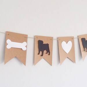 May include: A brown paper banner with alternating images of a pug, a bone, a heart, and a pug. The images are cut out and are white or black.