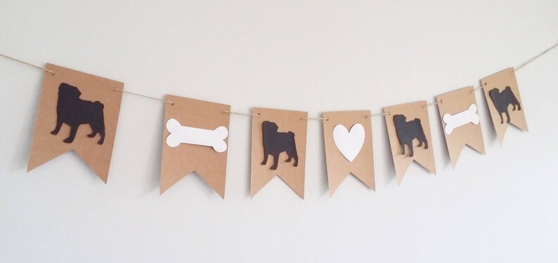 May include: A brown paper banner with alternating images of a pug, a bone, a heart, and a pug. The images are cut out and are white or black.