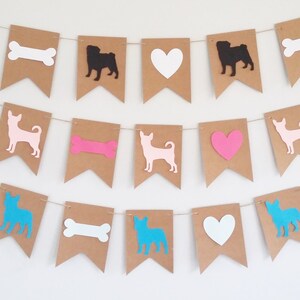 May include: A brown paper banner with cutouts of dogs, bones, and hearts. The dogs are in blue, pink, and black. The bones are in pink and white. The hearts are in pink and white.