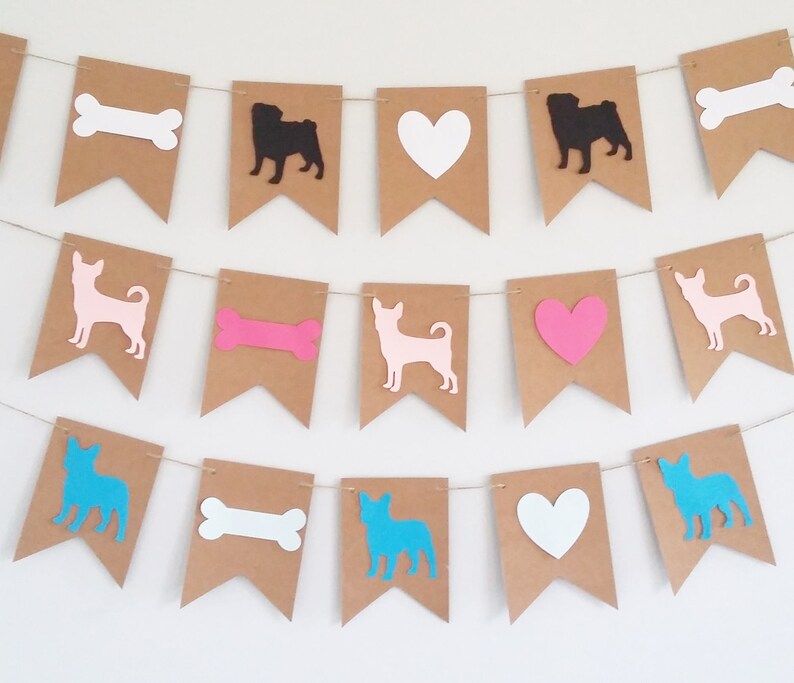 May include: A brown paper banner with cutouts of dogs, bones, and hearts. The dogs are in blue, pink, and black. The bones are in pink and white. The hearts are in pink and white.
