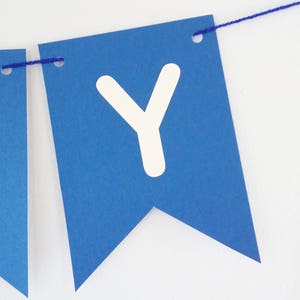 May include: Blue paper banner with white letter Y, strung with blue thread.