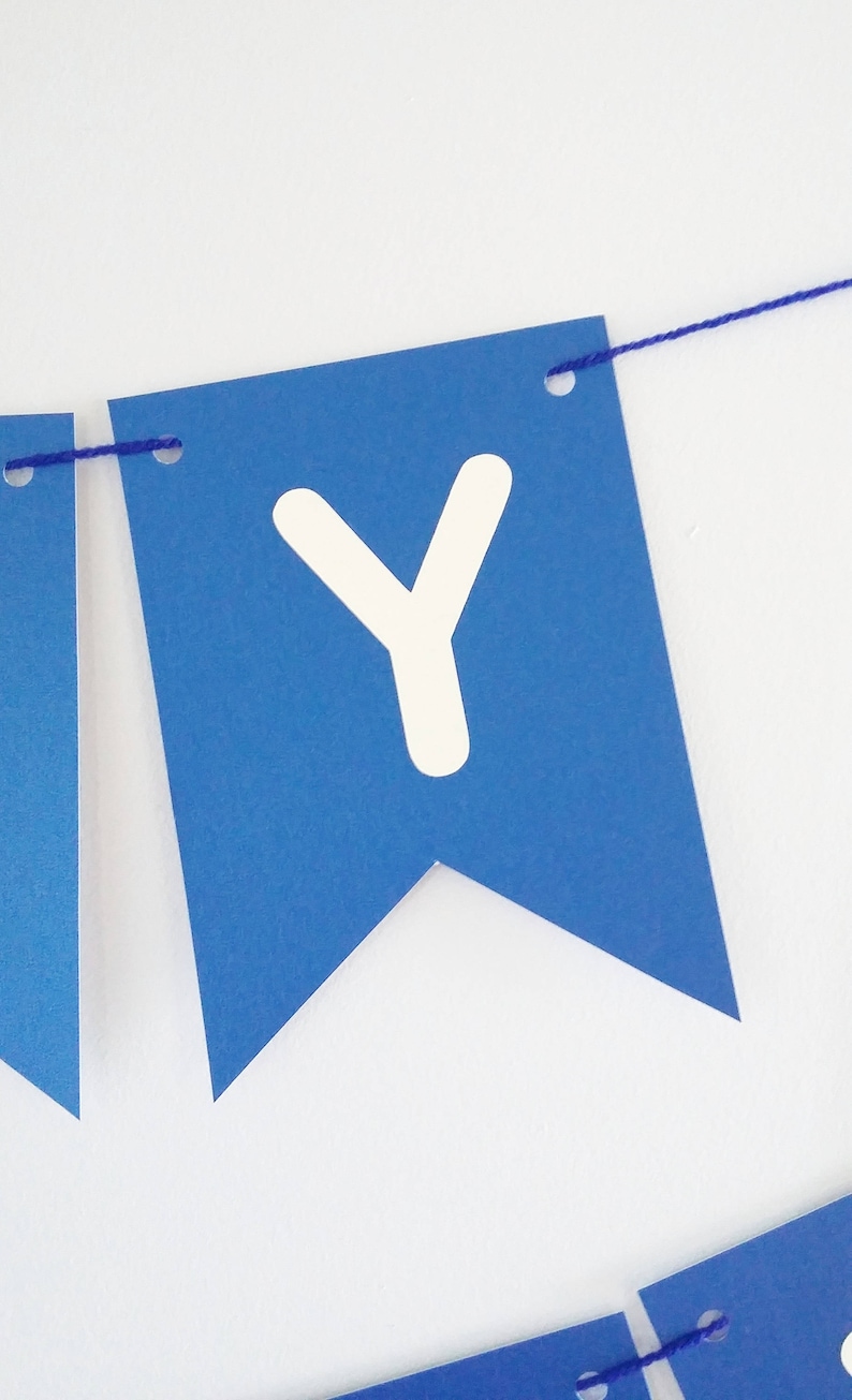 May include: Blue paper banner with white letter Y, strung with blue thread.