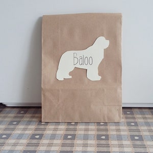 May include: A brown paper bag with a white silhouette of a dog on it. The dog's name, "Baloo", is written on the silhouette.