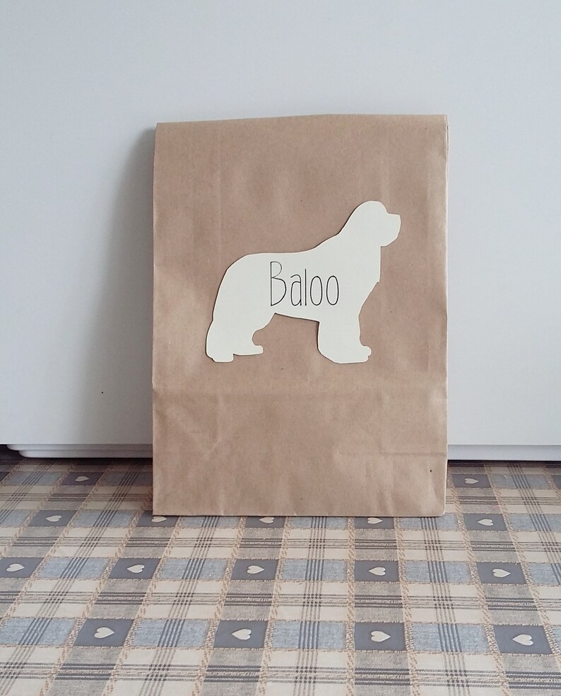 May include: A brown paper bag with a white silhouette of a dog on it. The dog's name, "Baloo", is written on the silhouette.