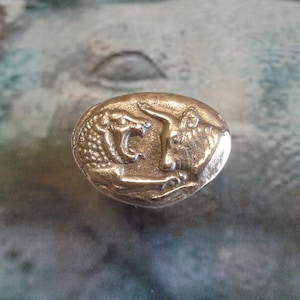 Peut inclure: Une bague en métal argenté avec un motif détaillé d'un lion et d'un taureau se faisant face.